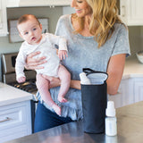 Woman holding baby with the All Bottle Cooler, black sitting on counter