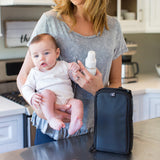 Woman holding baby with Pack ‘N Protect Cooler Bag for Glass Bottles and Containers sitting on counter