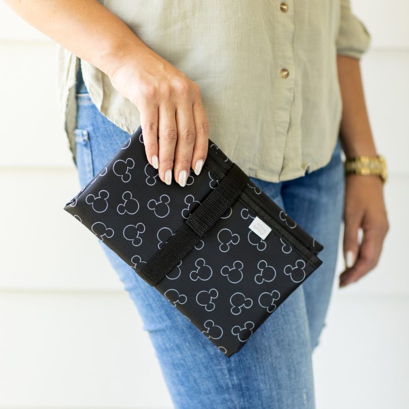 Woman holding Disney Baby Full Body Changing Pad, Mickey Black folded