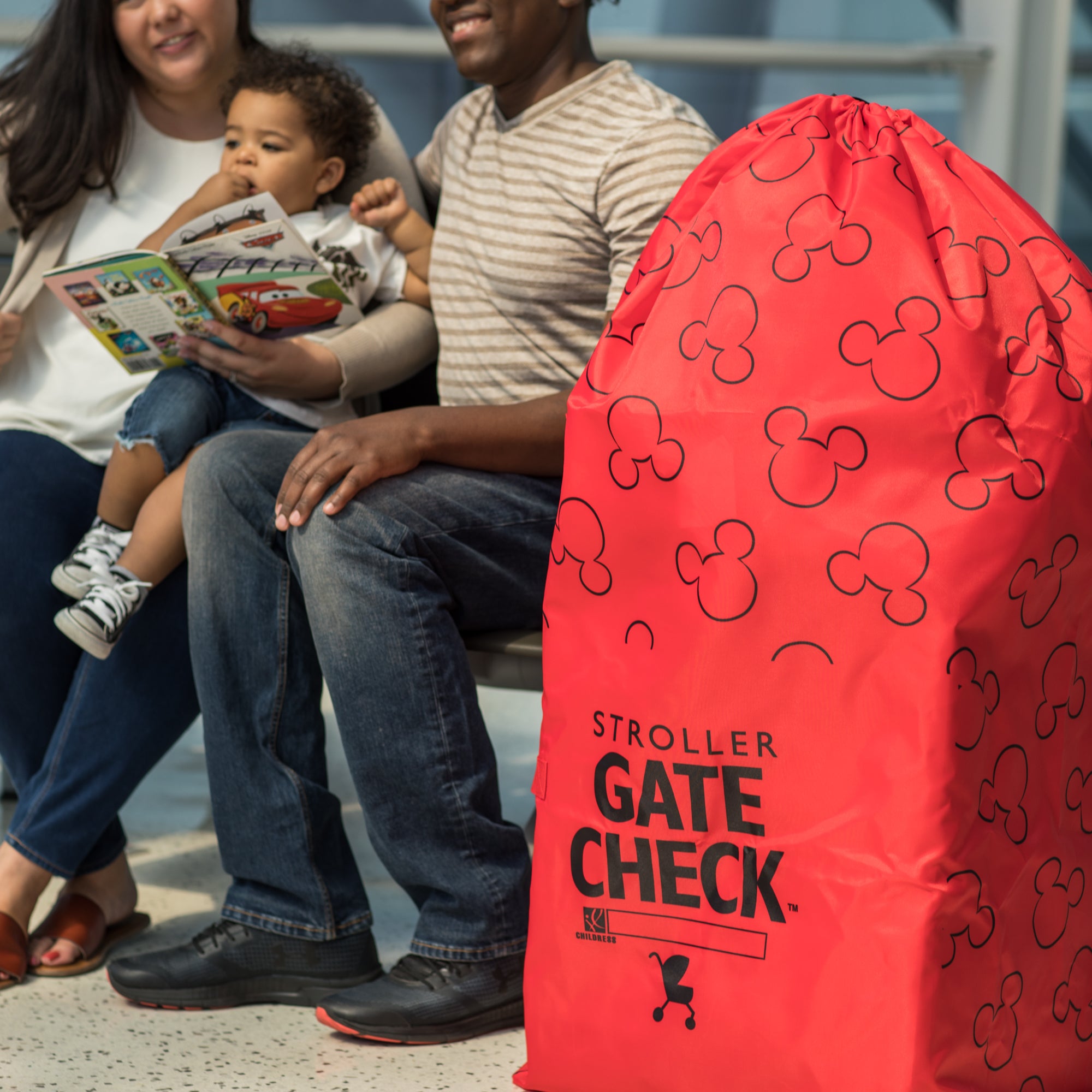 Family sitting down with Disney Baby Gate Check Travel Bag for Standard and Double Strollers sitting next to them