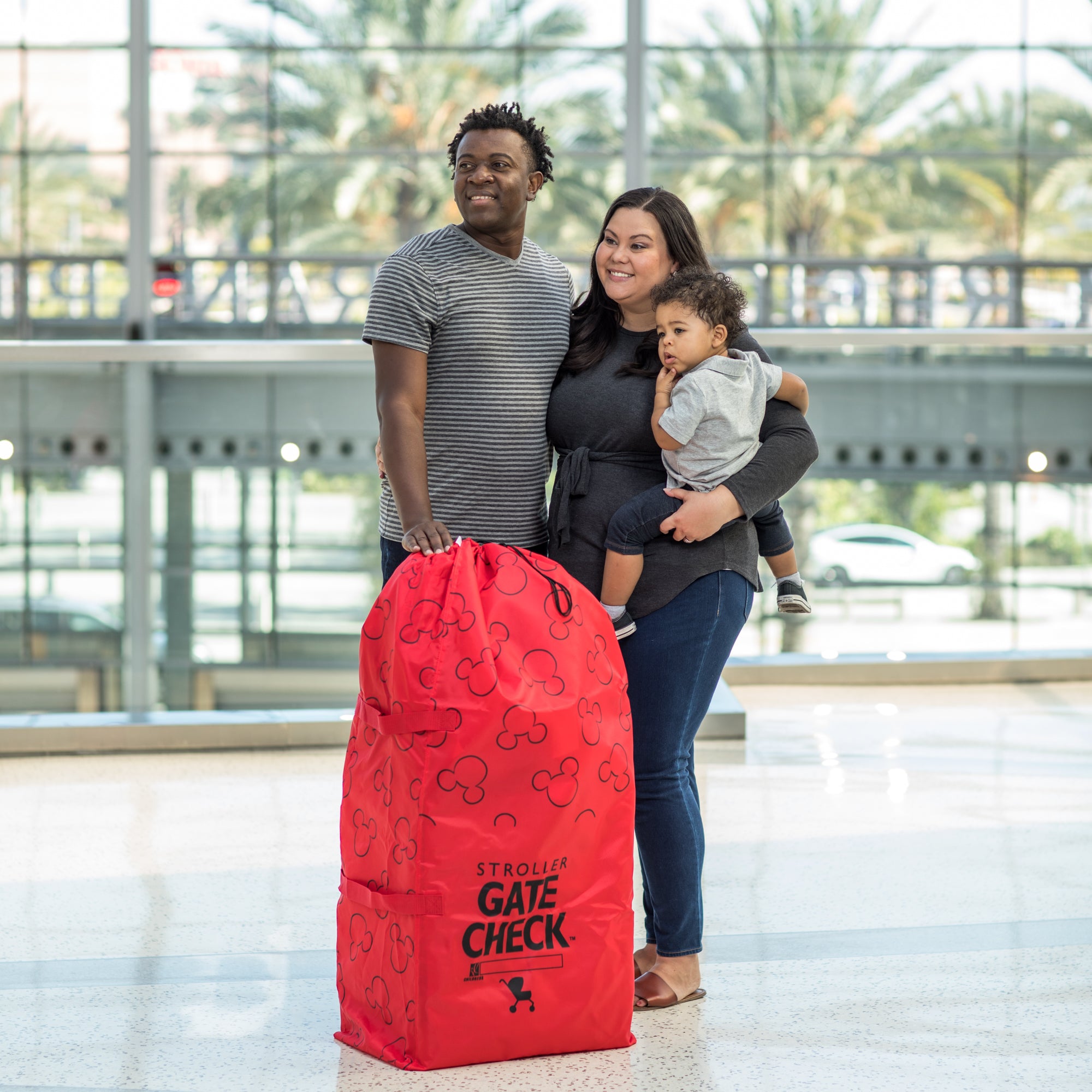 Family standing next to the Disney Baby Gate Check Travel Bag for Standard and Double Strollers