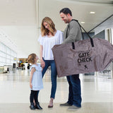Woman holding child's hand while man carries the Deluxe Gate Check Travel Bag for Standard & Double Strollers