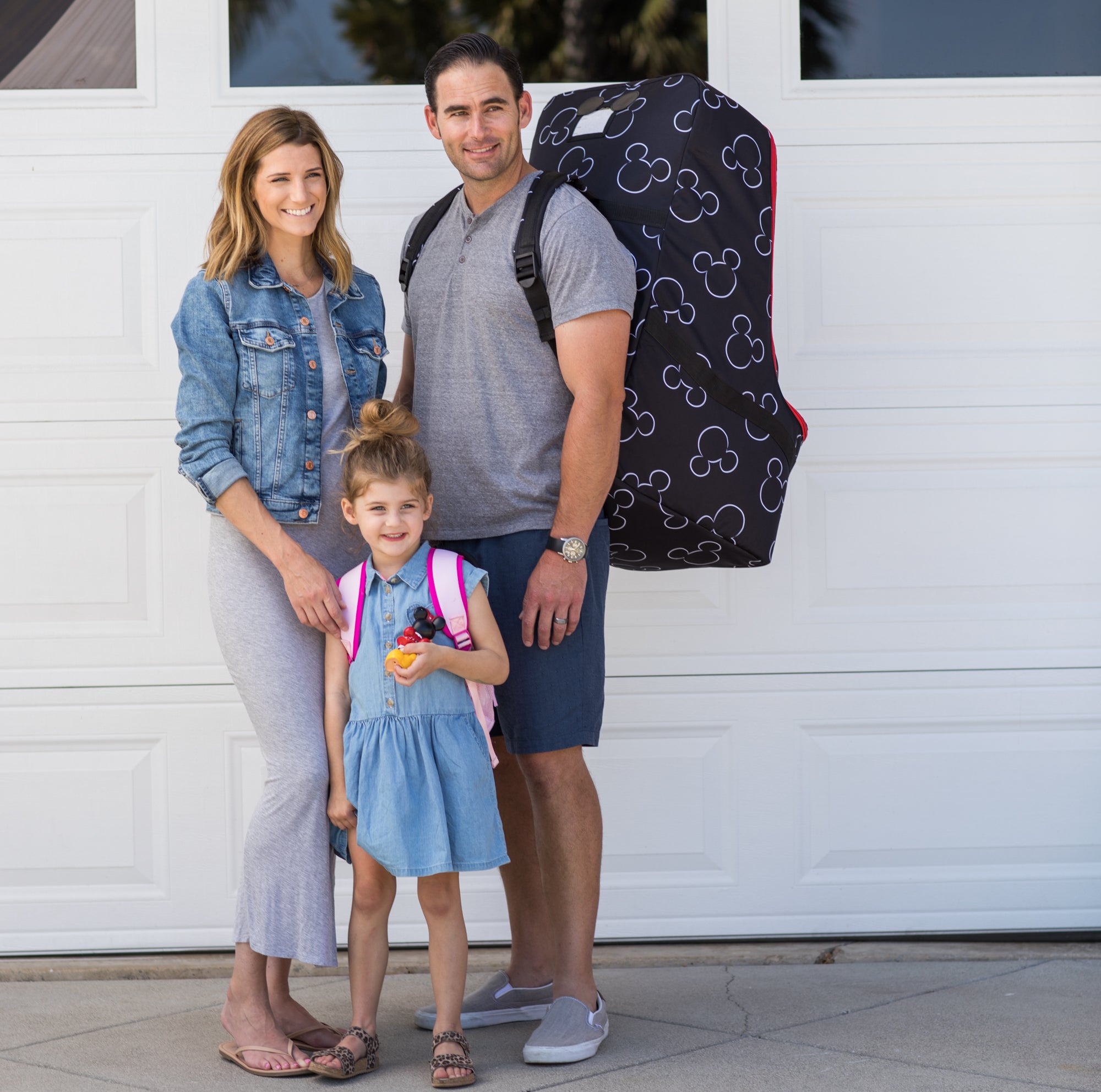 Family standing together with man carrying the Disney Baby Ultimate Padded Backpack Car Seat Travel Bag, Mickey Black