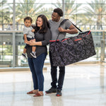Woman holding baby with man carrying the Disney Baby Single & Double Stroller Travel Bag, Mickey Black
