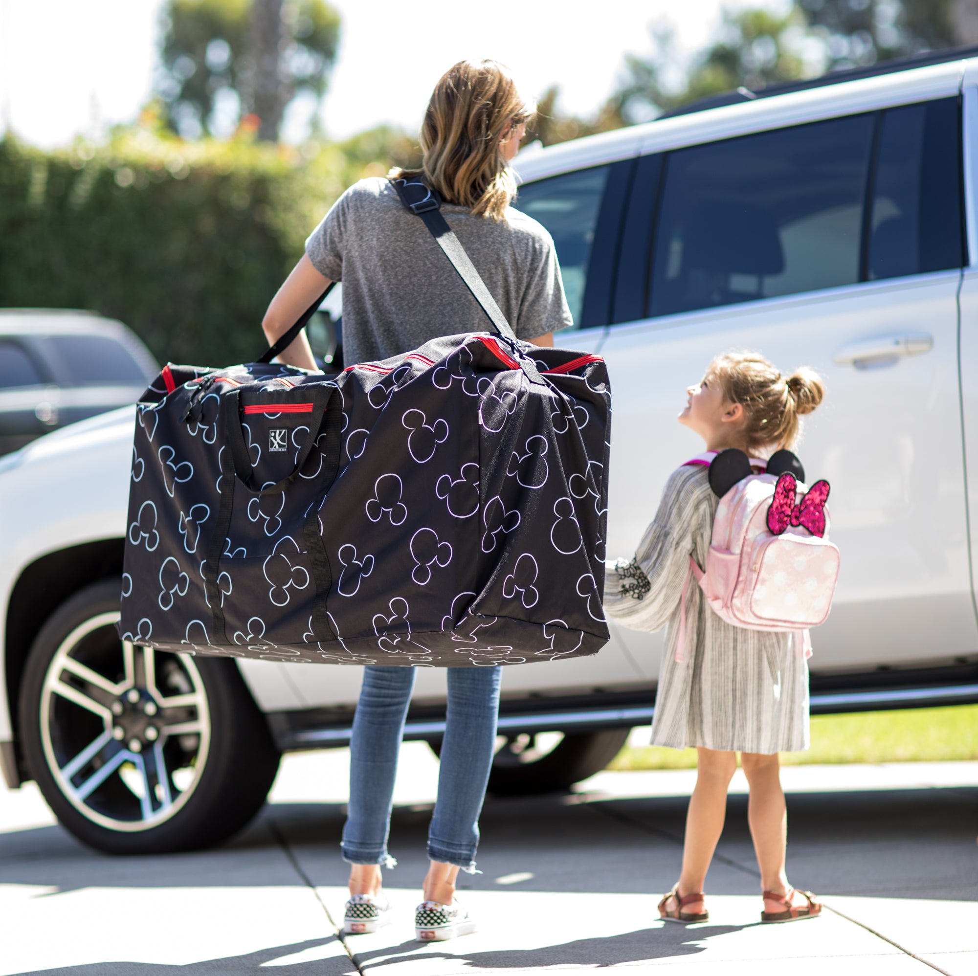 Woman walking with child holding the Disney Baby Single & Double Stroller Travel Bag, Mickey Black