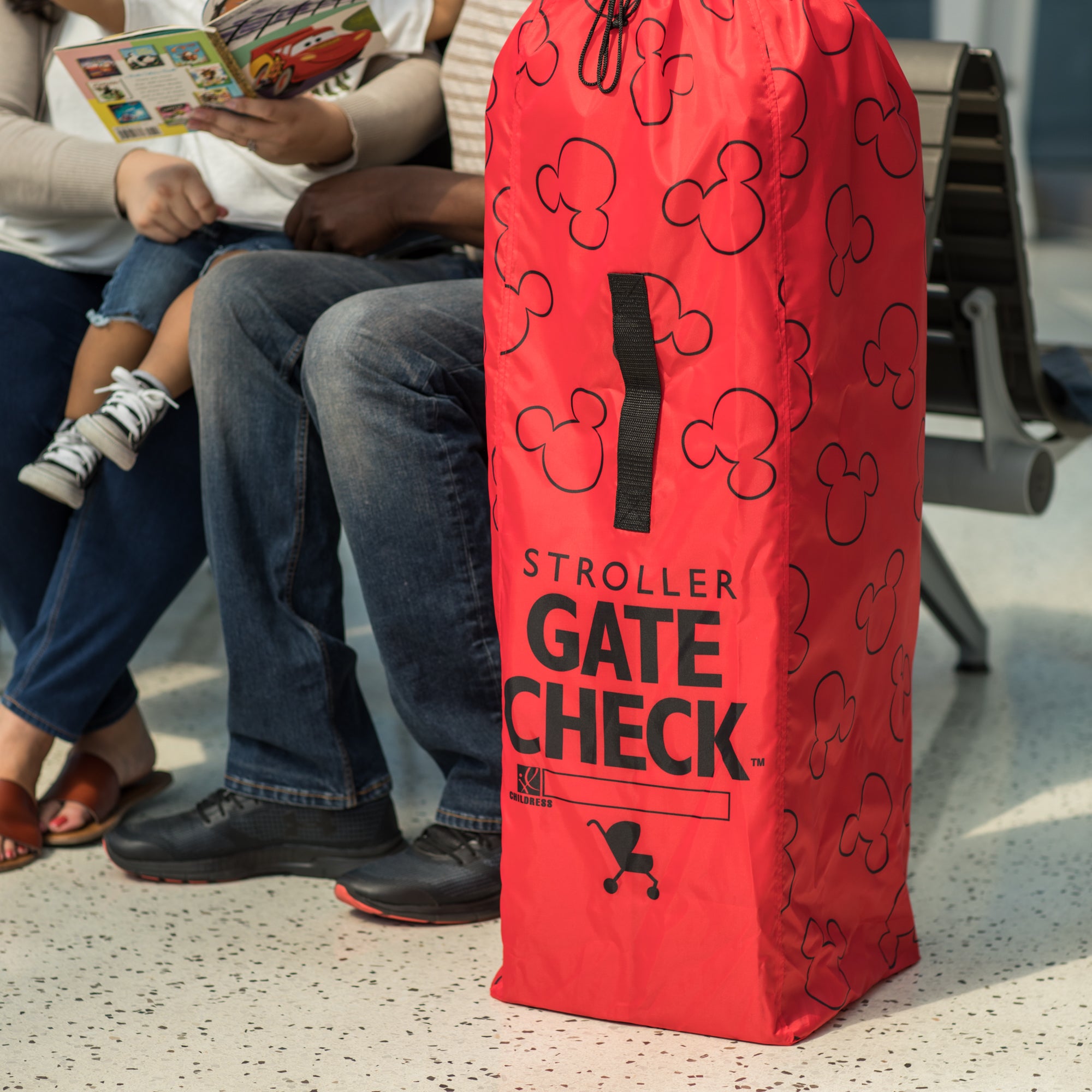 Family sitting next to the Disney Baby Gate Check Travel Bag for Umbrella Strollers