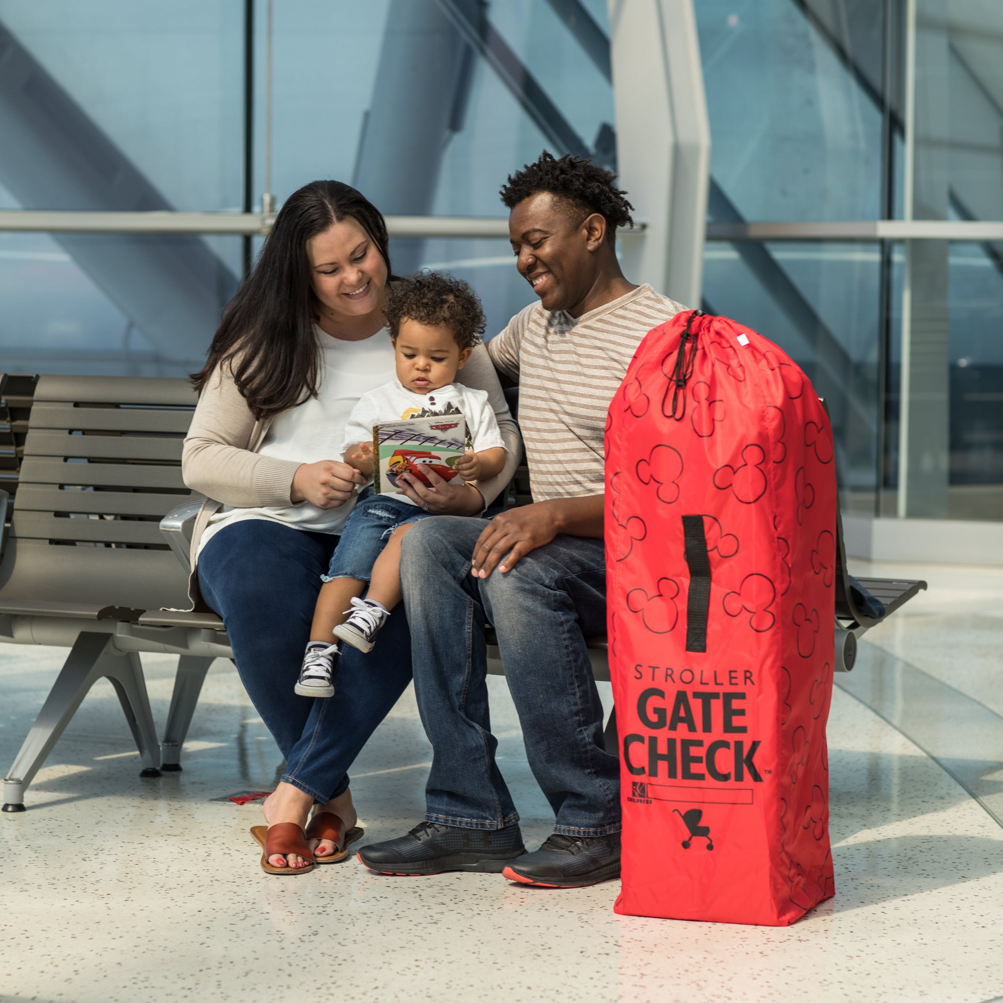 Family sitting next to the Disney Baby Gate Check Travel Bag for Umbrella Strollers