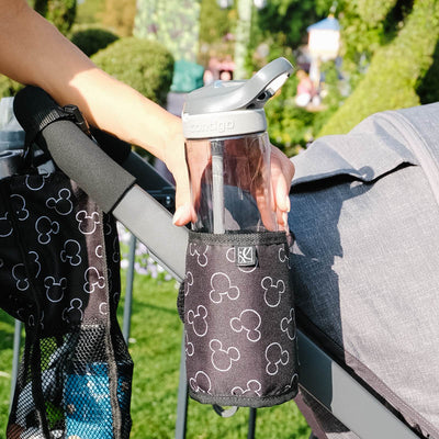 Disney Baby Cup ‘N Stuff Stroller Cup Holder hanging on stroller with woman pulling bottle out of it